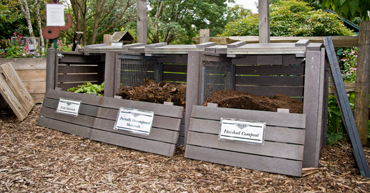 Three compost bins showing different stages of decomposition: the first with fresh plant materials, the second with partially decomposed matter, and the third with finished, dark compost.